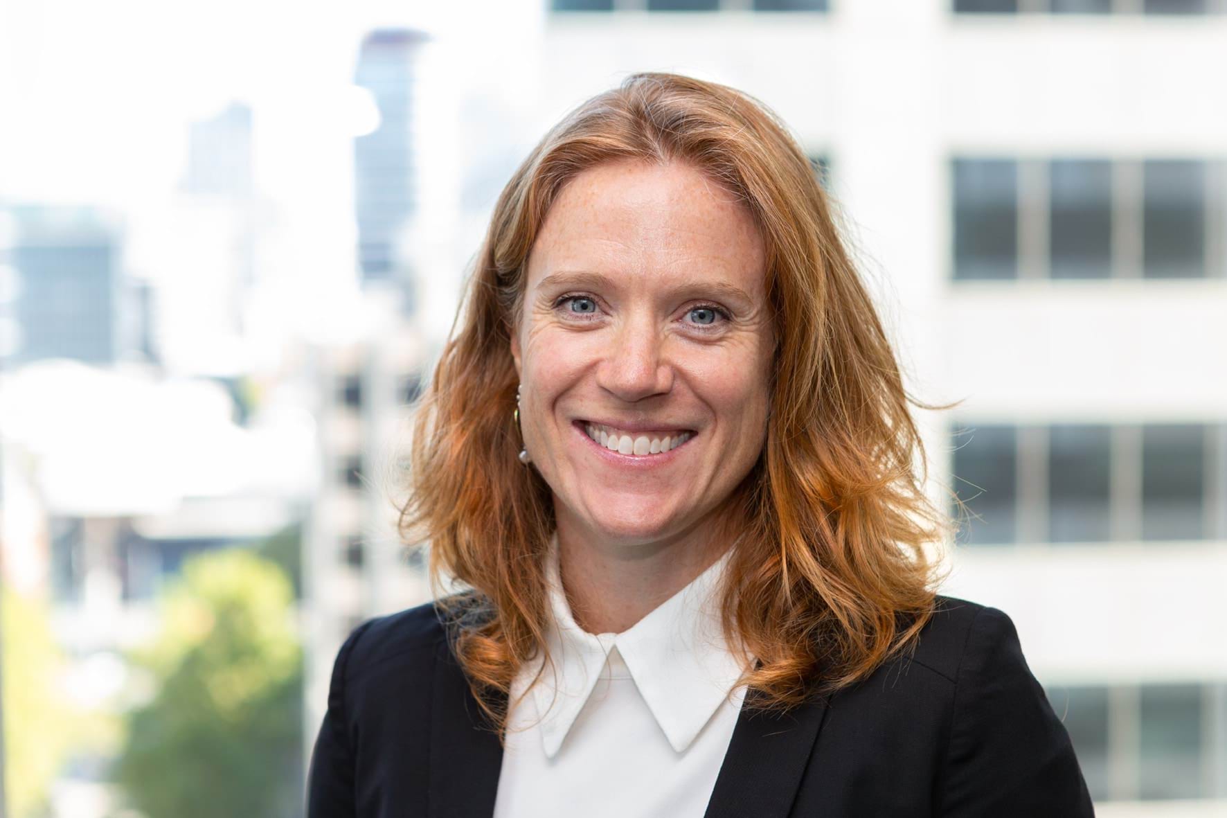 Profile photo of woman with long red hair smiling at camera.