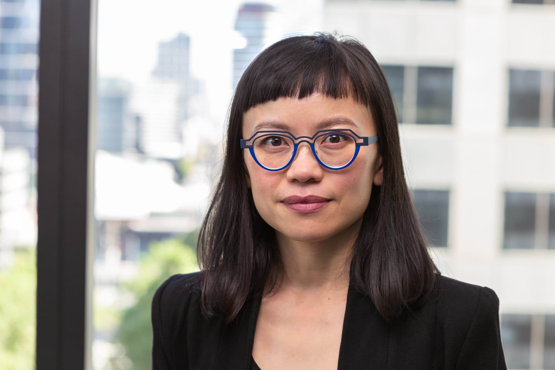 Profile photo of woman with shoulder length dark hair and glasses looking at camera.