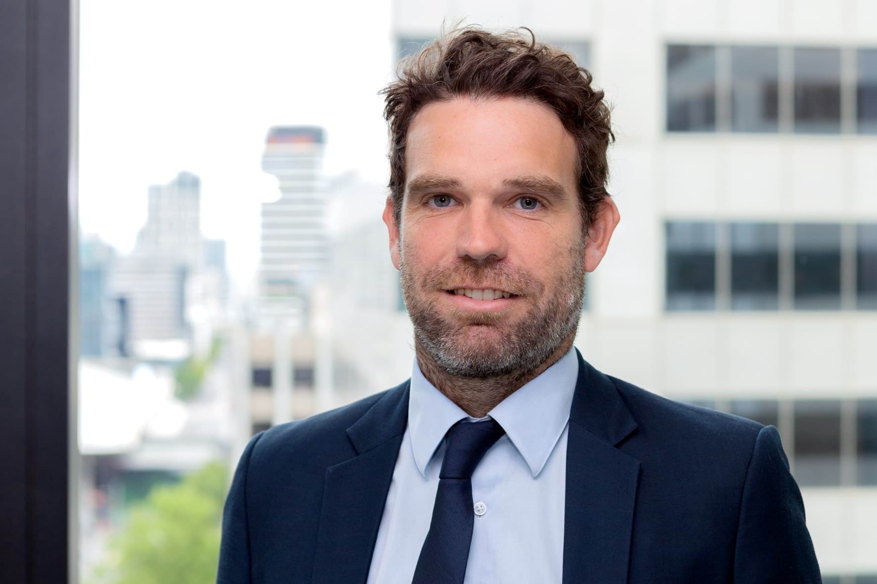 Profile photo of man with brown hair wearing a suit and smiling at camera