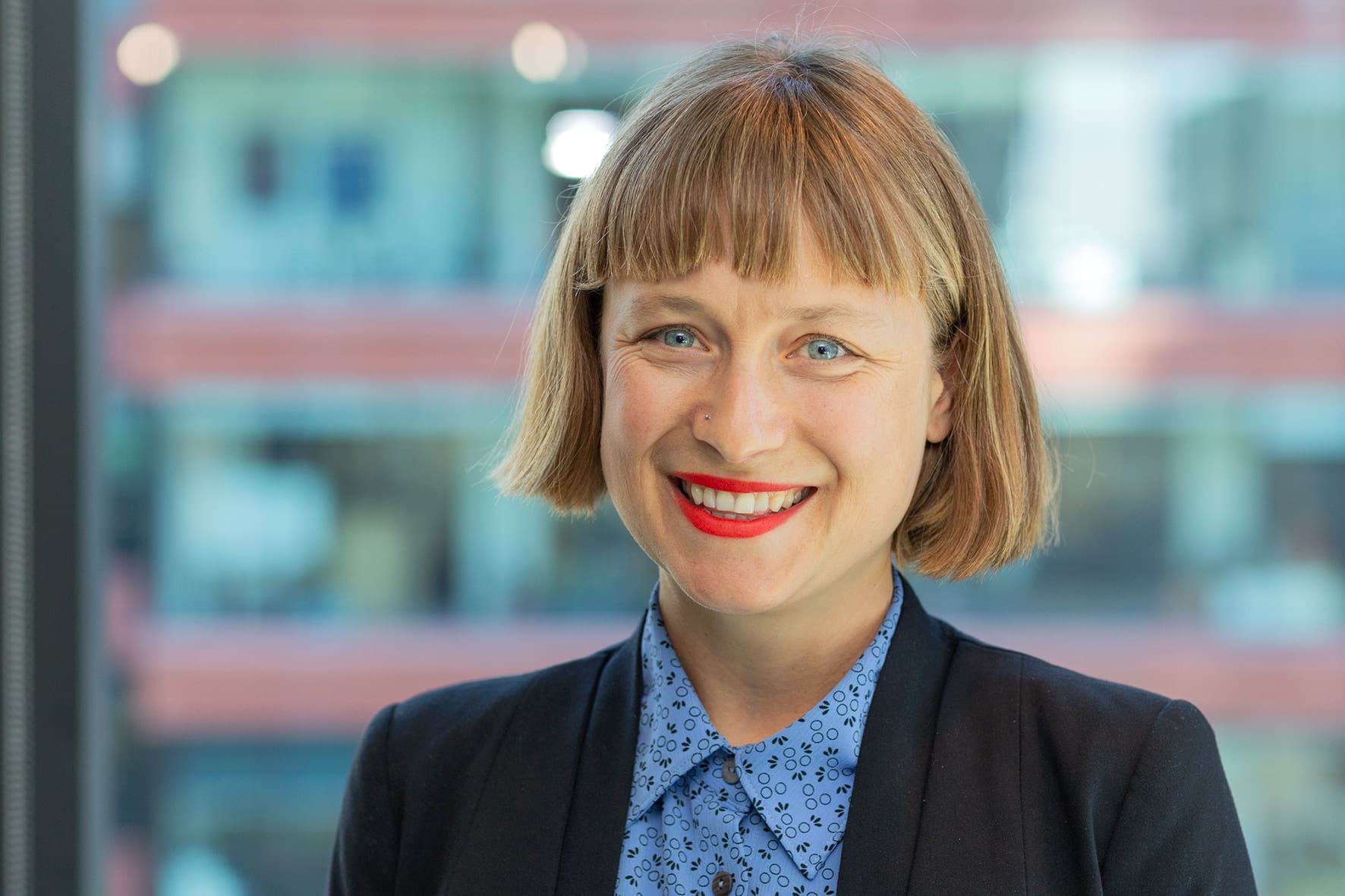 Profile photo of woman with short hair wearing a suit and smiling at camera.