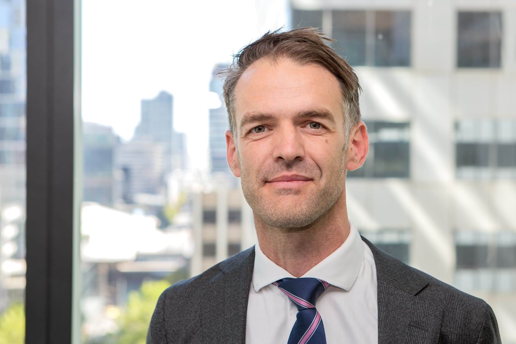 Profile photo of man wearing a suit and smiling at camera.