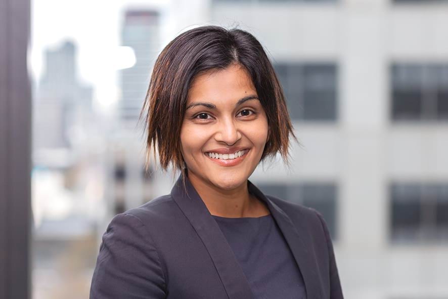 Profile photo of woman with short dark hair wearing a suit and smiling at camera.