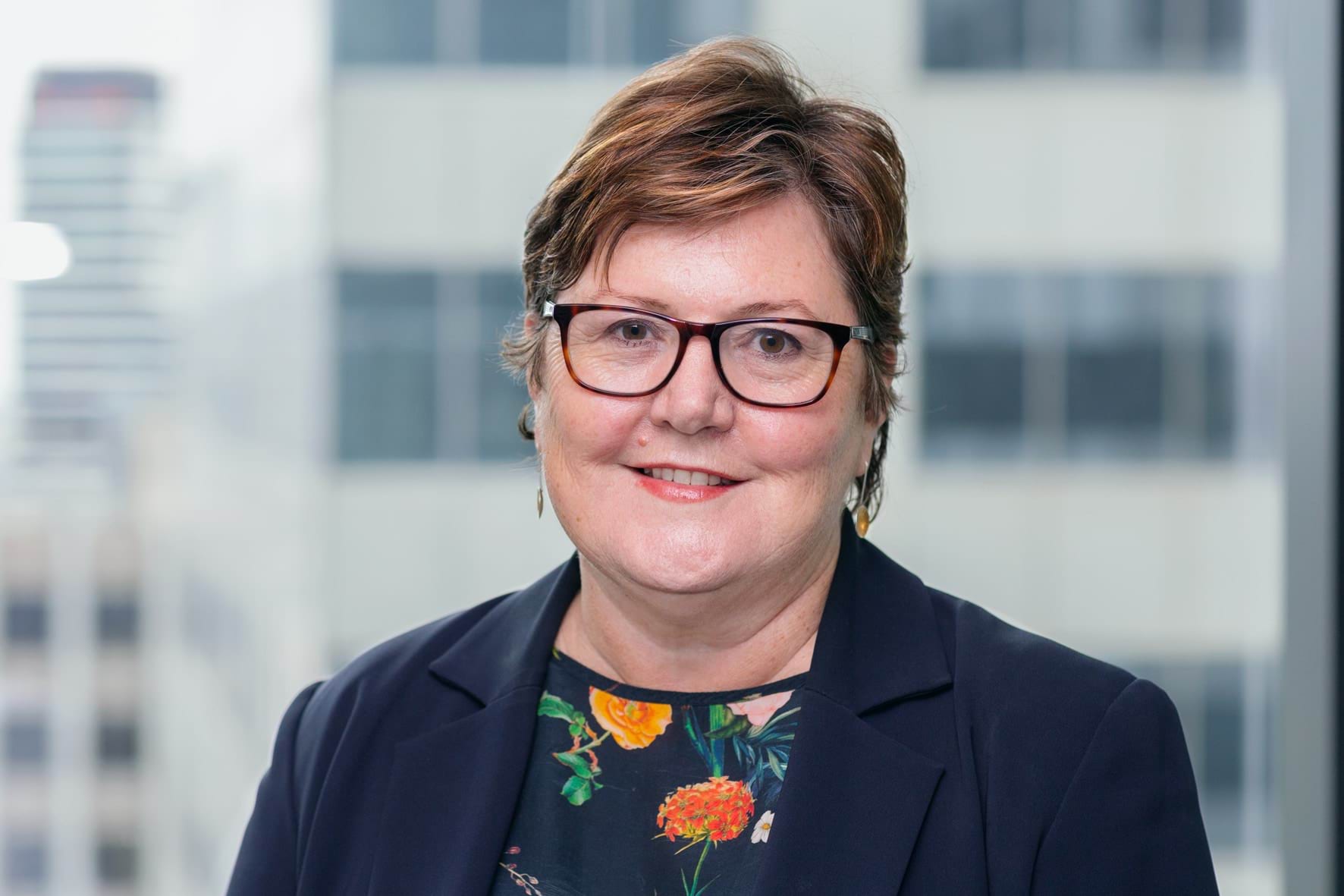 Profile photo of woman with short hair and glasses smiling at camera.