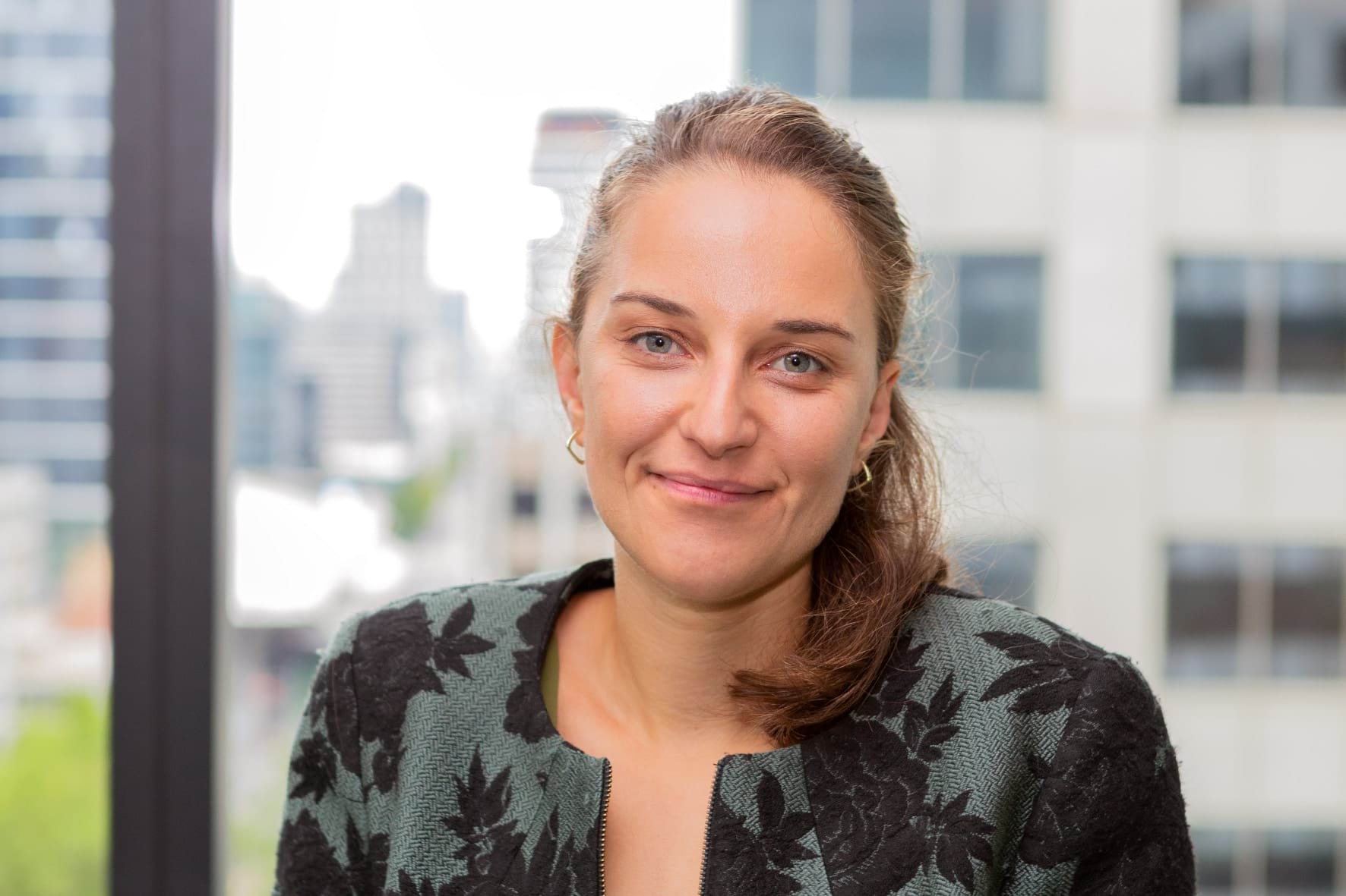 Profile photo of woman with brown hair tied up in ponytail smiling at camera.